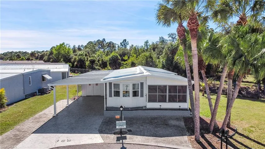 View of front of property with a front lawn, driveway, an attached carport, and a sunroom