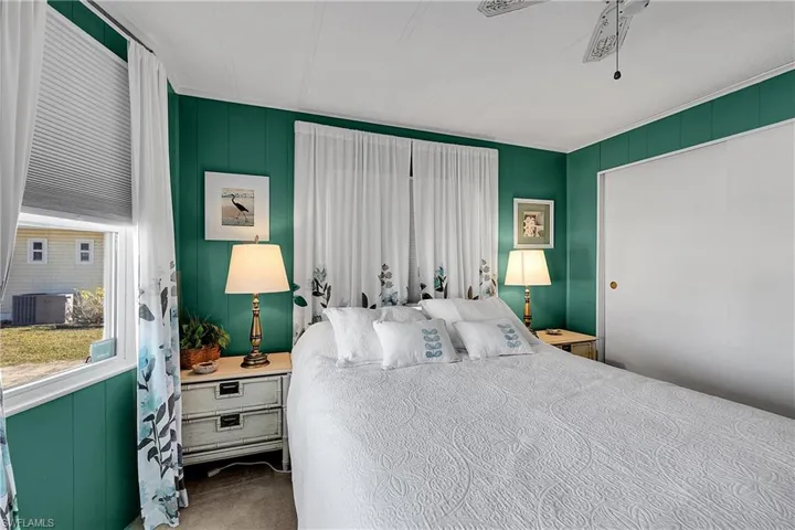 Carpeted bedroom with ceiling fan and wood walls