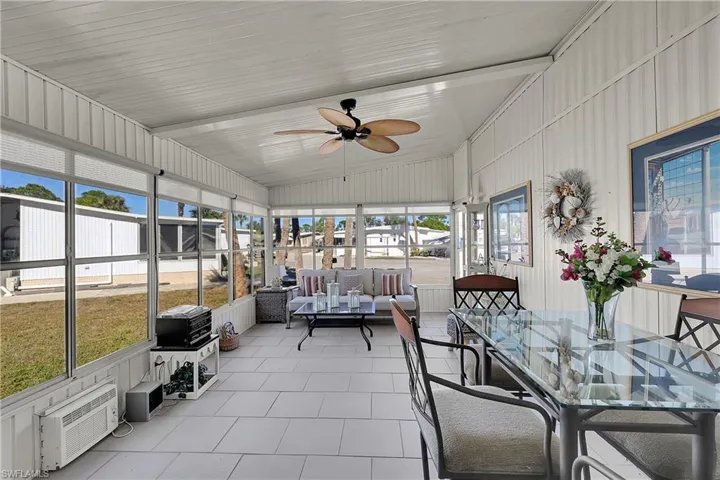 Sunroom with an outdoor living space, a ceiling fan, outdoor dining space, lofted ceiling, and a wall unit AC