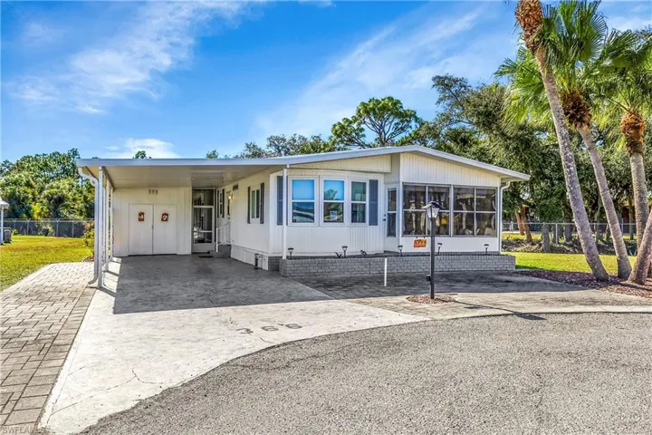 Manufactured / mobile home with a carport, driveway, and a sunroom