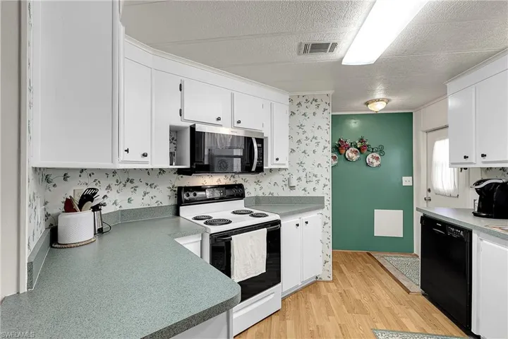 Kitchen featuring range with electric cooktop, dishwasher, white cabinetry, stainless steel microwave, and light wood finished floors