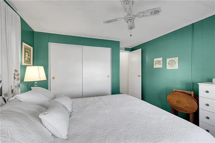 Bedroom with ceiling fan, crown molding, a closet, and wooden walls
