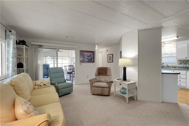 Living area with a textured ceiling and light colored carpet