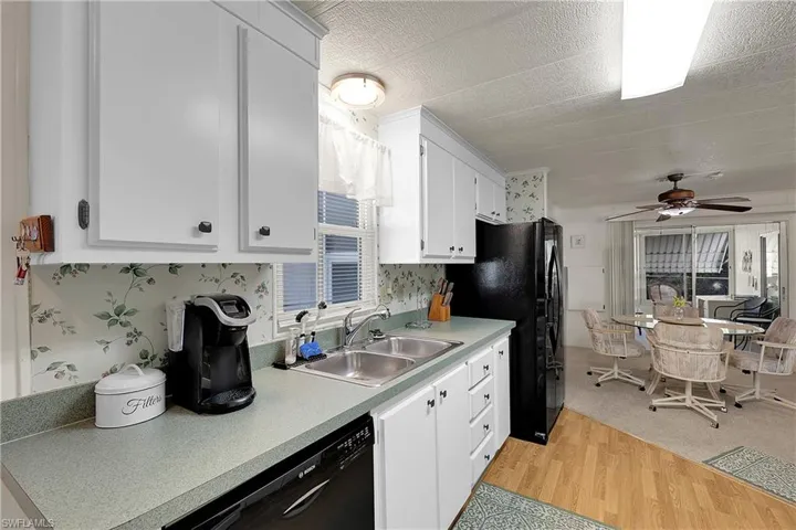 Kitchen featuring black appliances, white cabinets, light wood finished floors, light countertops, and ceiling fan
