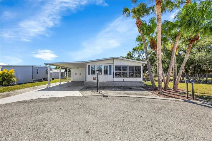 Manufactured / mobile home with driveway, a carport, and a sunroom
