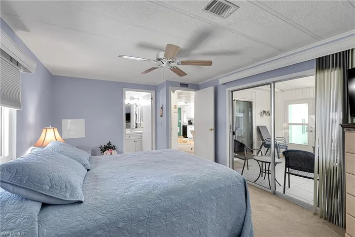 Carpeted bedroom with a ceiling fan, a textured ceiling, and connected bathroom