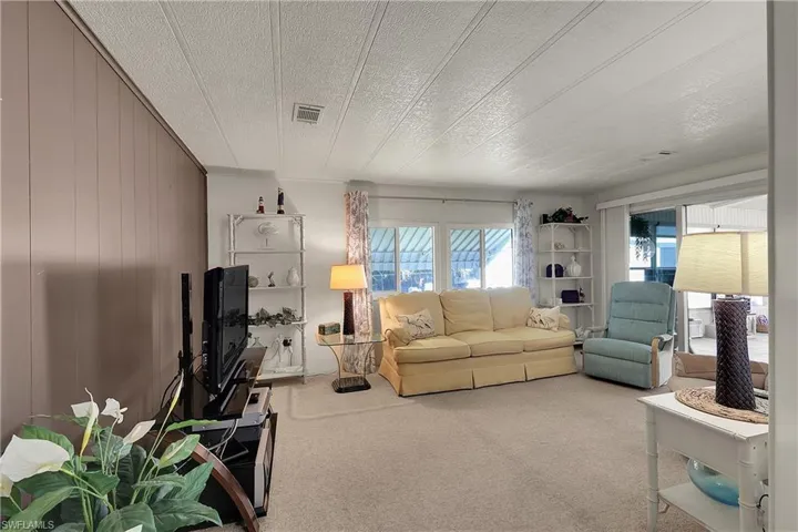 Living room with carpet flooring, wooden walls, and a textured ceiling