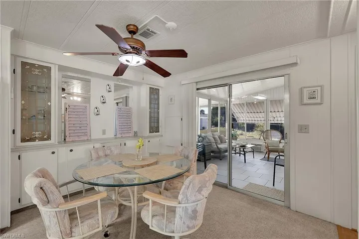 Dining area with carpet flooring, a ceiling fan, a textured ceiling, and a sunroom