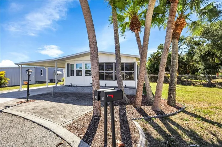 Manufactured / mobile home with a carport, driveway, and a sunroom