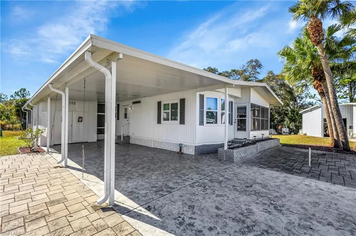 View of home's exterior featuring a patio, an attached carport, a sunroom, and driveway