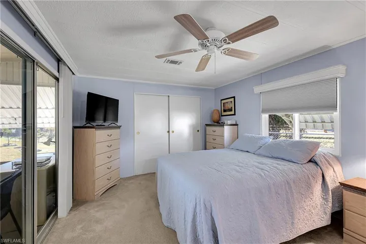 Bedroom featuring a closet, light carpet, a ceiling fan, and a textured ceiling