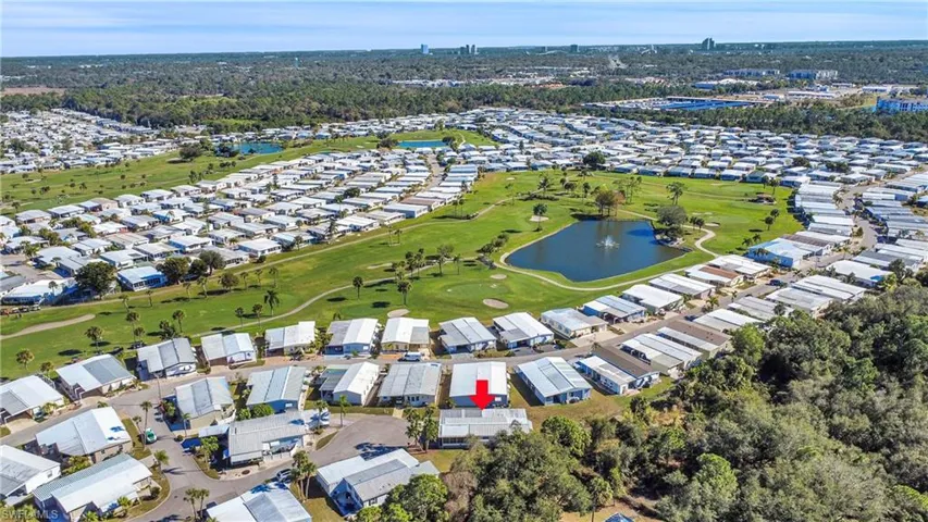 Aerial view of property and surrounding area featuring a nearby body of water, nearby suburban area, and a local golf course