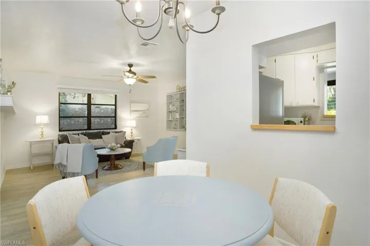 Dining room with ceiling fan with notable chandelier and light luxury vinyl wood-style flooring