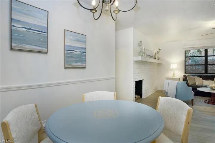 Dining area featuring a chandelier, a faux brick fireplace, and light luxury vinyl wood-style floors