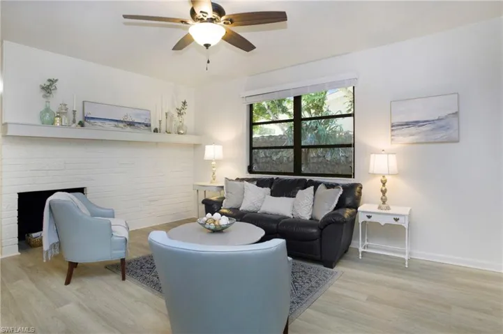 Living room featuring a faux brick fireplace, ceiling fan, and light luxury vinyl wood-style flooring