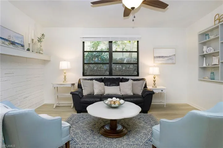 Living room with built in features, ceiling fan, and luxury vinyl wood-style flooring