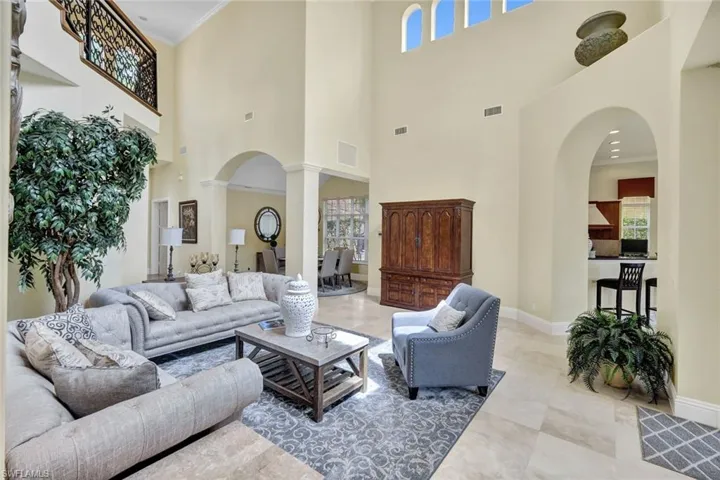 Living room with a high ceiling, ornamental molding, and ornate columns