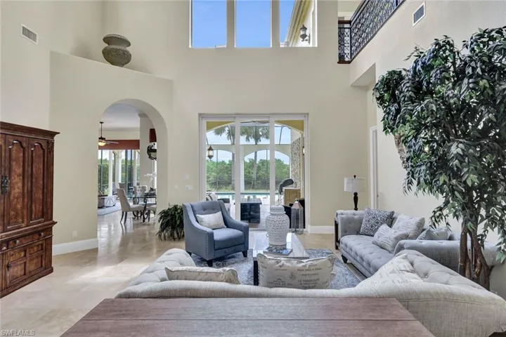 Living room featuring travertine floors, a high ceiling, and tons of light