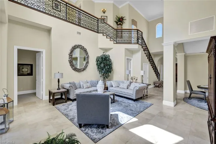 Living room with a towering ceiling, crown molding, and decorative columns