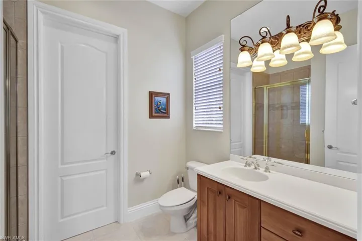 Bathroom featuring tile flooring, vanity, toilet, and shower