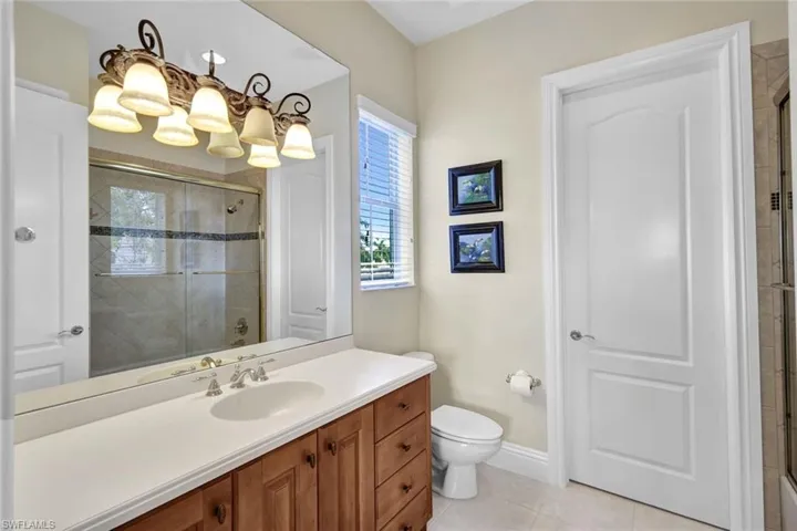 Bathroom featuring tile flooring, vanity, toilet, and an enclosed shower