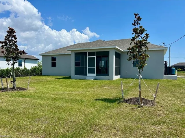 Back of house featuring a sunroom, roof with shingles, a yard, and stucco siding