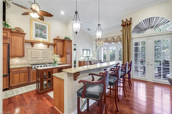 Kitchen with brown cabinetry, tasteful backsplash, healthy amount of natural light, dark wood-type flooring, and ornamental molding