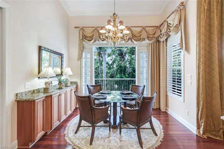 Dining area with arched walkways, a chandelier, crown molding, dark wood-type flooring, and baseboards