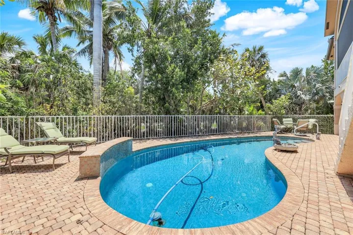 View of pool featuring fence, stairway, a patio area, and view of wooded area