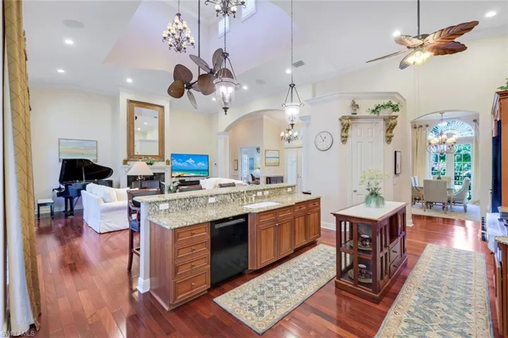 Kitchen featuring a kitchen island, brown cabinetry, dark wood-type flooring, ornamental molding, and recessed lighting