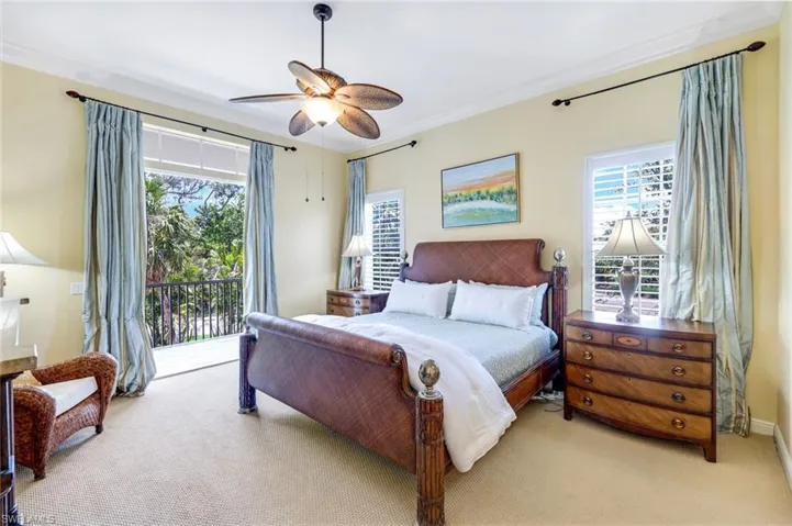 Carpeted bedroom featuring ornamental molding, ceiling fan, and baseboards