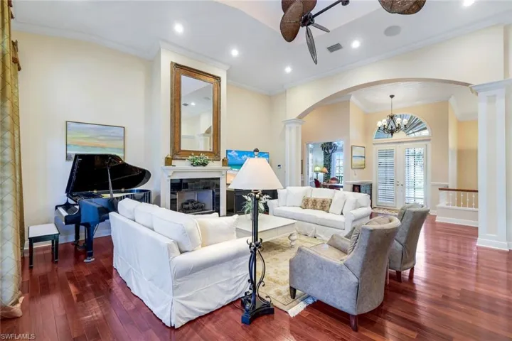 Living room with a chandelier, ceiling fan, crown molding, dark wood-style floors, and recessed lighting