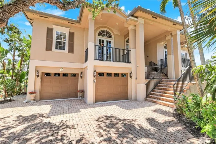 Living area with arched walkways, ceiling fan, ornamental molding, decorative columns, and dark wood finished floors