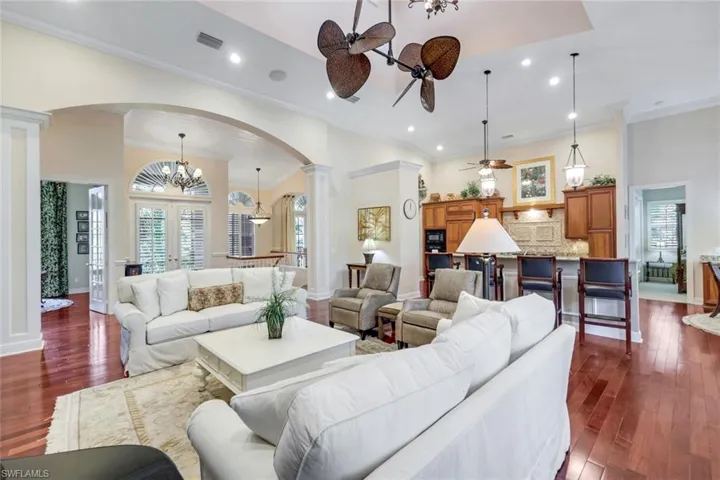Living area with dark wood-type flooring, crown molding, a fireplace, ceiling fan, and recessed lighting