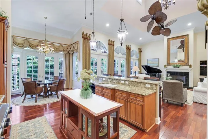 Kitchen featuring a chandelier, black dishwasher, arched walkways, a breakfast bar area, and brown cabinets