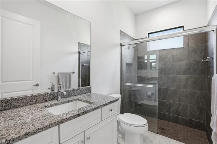Full bathroom featuring a white vanity with a granite countertop, undermount sink, and polished chrome faucet
