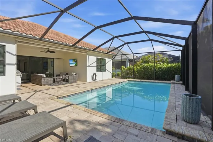 Screened pool area featuring a blue-tiled swimming pool and surrounding paver patio