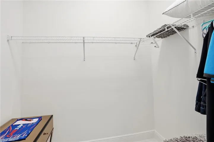 Walk-in closet featuring white wire shelving and hanging rods