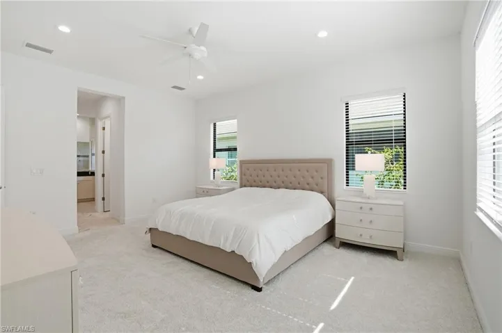 Spacious bedroom featuring plush carpeting, dual windows with blinds, and recessed lighting