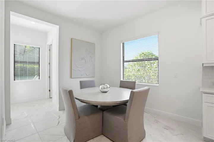 Bright dining area featuring white walls, large windows, and white tile flooring