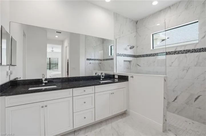 Dual vanity with dark stone countertop, white cabinetry, and undermount sinks