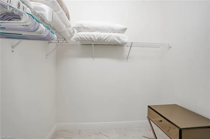 Closet featuring wire shelving, white walls, and marble-finish flooring