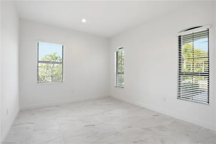 Spacious room featuring light-toned large format tile flooring and multiple windows with blinds