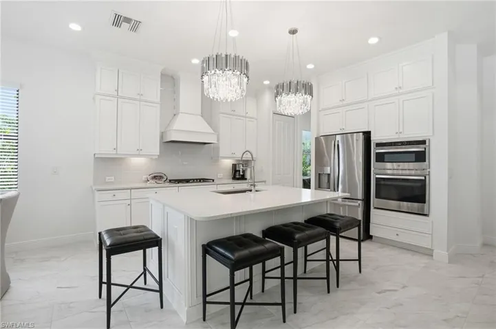 Gourmet kitchen featuring a large island with seating, stainless steel appliances, white shaker cabinetry, and recessed lighting