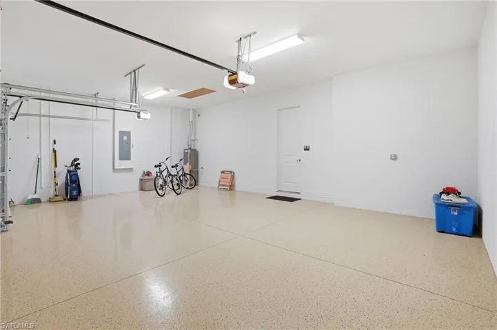 Spacious garage featuring a light-colored speckled epoxy floor, overhead fluorescent lighting, and a white access door
