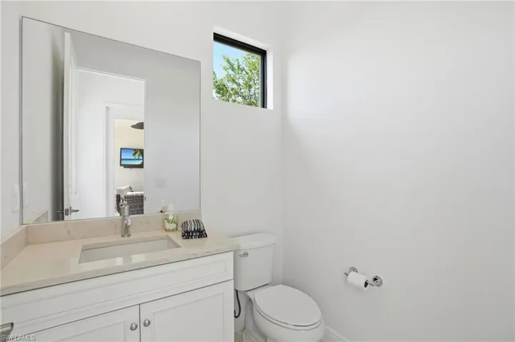 Contemporary bathroom featuring a white vanity with a light-toned countertop, an undermount sink, and a large frameless mirror