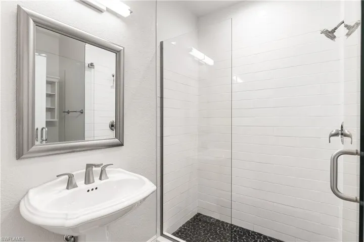 2nd bathroom has freesatndug vanity, floor to ceiling tile, seamless glass shower enclosure.