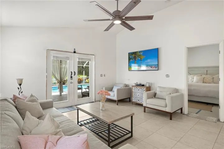 Living room with light tile patterned flooring, french doors, high vaulted ceiling, and ceiling fan