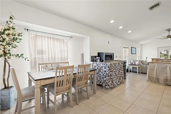 Dining space with vaulted ceiling, light tile patterned floors, and ceiling fan