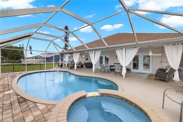 View of swimming pool featuring a patio, an in ground hot tub, french doors, and glass enclosure